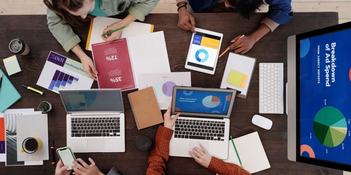 A diverse team collaborating on digital marketing strategies at a desk, using laptops and tablets.